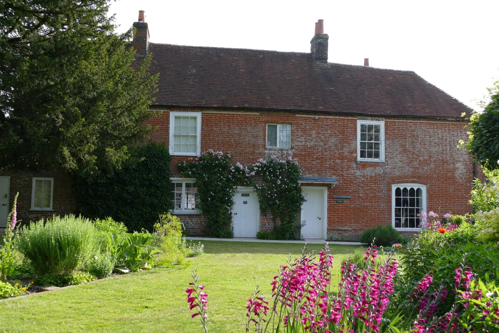 Brick house with shrubs, lawn, and flowers